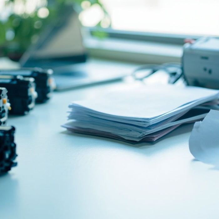 neat office desk with toner cartridges, paper, laptop under soft daylight