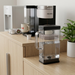 Keurig K-2500 3.25L water reservoir on a conference breakroom side table, with a coffee cart and plant.