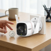 TP-Link Tapo-C320WS outdoor camera compared for size against a US quarter dollar on a wooden desk.